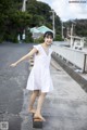 A woman in a white dress standing on a concrete block.