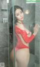 A woman in a red bathing suit standing in a shower.