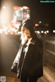 A woman standing on a sidewalk at night in the city.