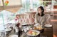 A woman sitting at a table with plates of food.