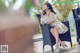 A woman sitting on a chair holding a cup of coffee.