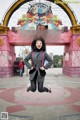 A woman is jumping in the air in front of a gate.