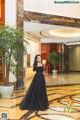 A woman in a black dress standing in a lobby.