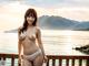 A woman in a white bikini standing on a wooden deck.