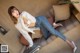 A woman sitting on top of a couch next to a suitcase.