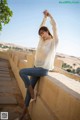 A woman sitting on a wall with her arms outstretched.