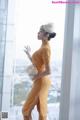 A woman in a yellow dress standing by a window.