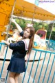 A woman in a school uniform leaning against a fence.