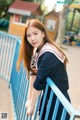 A woman in a school uniform leaning against a railing.