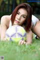 A woman laying on the grass with a soccer ball.