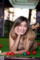 A woman laying on top of a pool table.