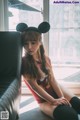 A woman sitting on a couch wearing a mickey mouse ears headband.