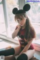 A young woman wearing a mickey mouse ears headband sitting on the floor.