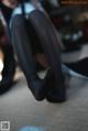 A woman in black stockings and high heels sitting on the floor.