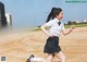 A young girl in a school uniform running on a dirt field.