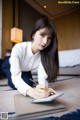 A woman sitting on the floor writing in a notebook.