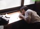 A woman sleeping on a desk next to a window.