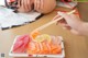 A person holding chopsticks over a plate of sushi.