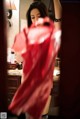 A woman in a red dress standing in front of a mirror.