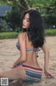 A woman in a bikini sitting on the sand.