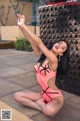 A woman in a pink bathing suit sitting on the ground.