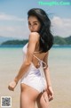 A woman in a white bathing suit standing on a beach.