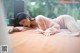 A woman laying on a bed in a pink robe.