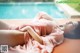 A woman laying on the edge of a swimming pool.