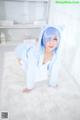 A woman in a blue cat costume crouching on a white rug.