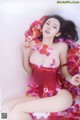 A woman in a red dress laying on a bed of rose petals.