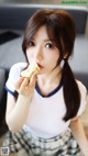 A young woman eating a piece of food on a table.