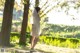 A woman in a white dress is walking in the park.