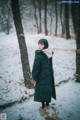 A woman standing in the snow in the woods.