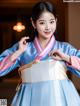 A woman in a blue and white hanbok posing for a picture.