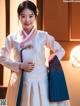 A woman in a white and blue hanbok is posing for a picture.