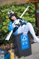 A woman sitting in a trash can holding a baseball bat.