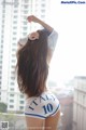 A woman in a white shirt and blue shorts standing on a balcony.