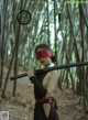 A woman in a black dress holding a sword in a forest.