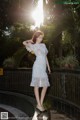 A woman in a white dress standing on a bridge.