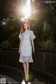 A woman in a white dress standing on a bridge.