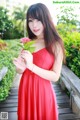 A woman in a red dress holding a flower.