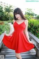 A woman in a red dress posing on a wooden bridge.