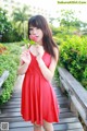 A woman in a red dress holding a flower.