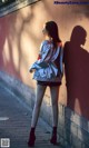 A woman leaning against a wall with her shadow on the wall.