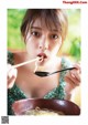 A woman eating a bowl of noodles with chopsticks.