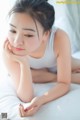 A woman laying on a bed with her hand on her chin.