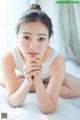 A woman laying on a bed with her hand on her chin.