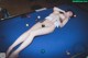 A woman laying on top of a pool table.