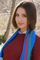 A woman wearing a red sweater and a blue scarf.