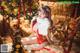 A woman in a red and white lingerie sitting next to a Christmas tree.